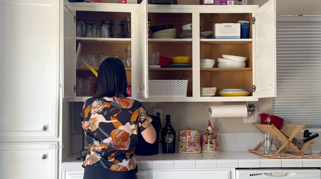 Woman in her kitchen with the cabonet doors open